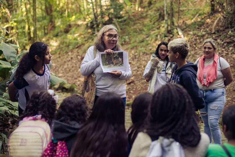 Educadora mostra a um grupo de estudantes uma prancha impressa com a foto de um animal da Mata Atlântica.